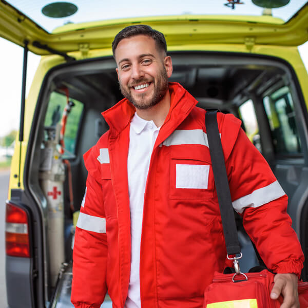 young-man-paramedic-standing-rear-ambulance-by-open-doors-he-is-looking-camera-with-confident-expression-smiling-carrying-medical-trauma-bag-his-shoulder (1)